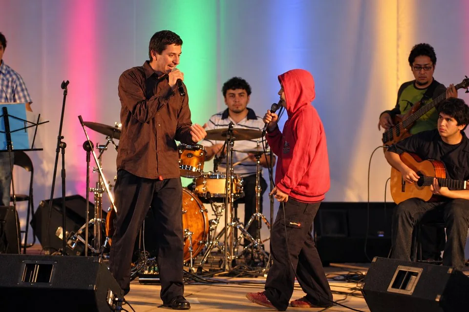 Alejandro Luna cantando con un niño en el escenario, con su banda